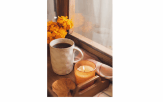 autumn next to window with orange flowers, coffee, and candle burning