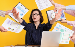 overwhelmed woman in business with hands shoving documents and files in her face.